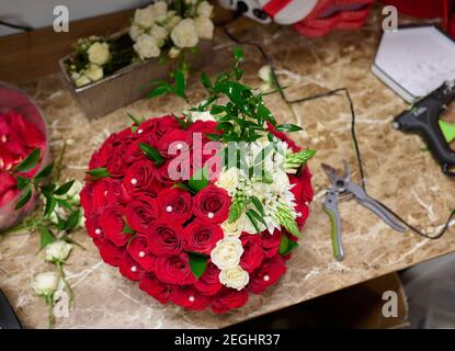 Flower box with red roses and white flowers on the table, flower box assembly process Stock Photo