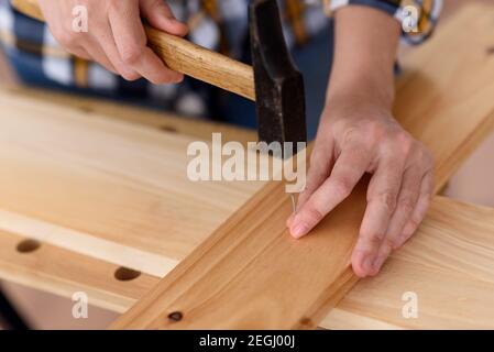 close up of young woman assembling furniture at home working with hammer. DIY concept. High quality photo Stock Photo