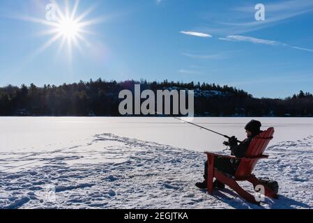 Teen boy ice fishing on a frozen lake in Canada on a winter day Stock Photo  - Alamy