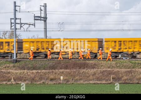 Network Rail track workers walk the line near Bourton in Wiltshire as a ballast train passes on the mainline Stock Photo