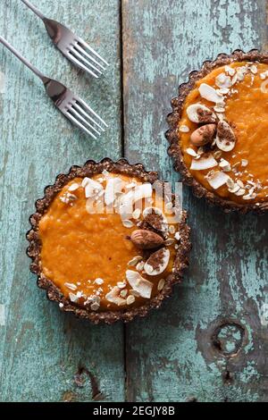 Healthy vegetarian diet. Tasty pumpkin tarts decorated with almonds and oatmeal on old blue table above view Stock Photo