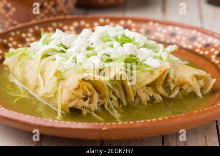 Mexican green chicken enchiladas served on a traditional clay plate Stock Photo