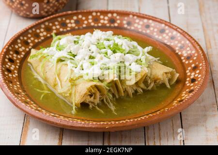 Mexican green chicken enchiladas served on a traditional clay plate Stock Photo