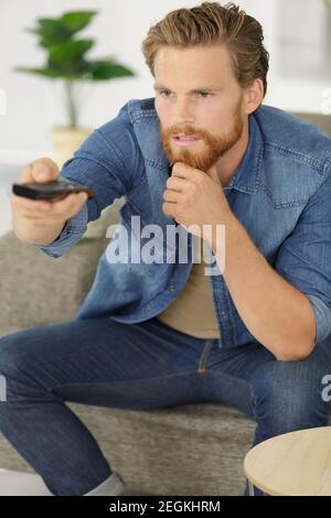 man changes the channels on the remote control Stock Photo