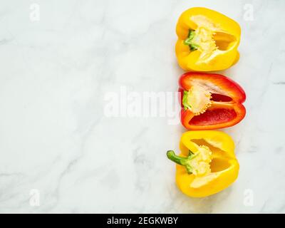 Red and yellow bell peppers sliced by the half with seeds isolated in kitchen counter viewed from above Stock Photo