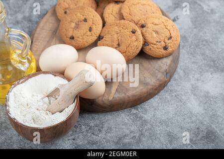 Oatmeal cookies with chocolate drops on a wooden board with ingredients around Stock Photo