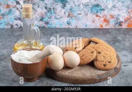 Oatmeal cookies with chocolate drops on a wooden board with ingredients around Stock Photo