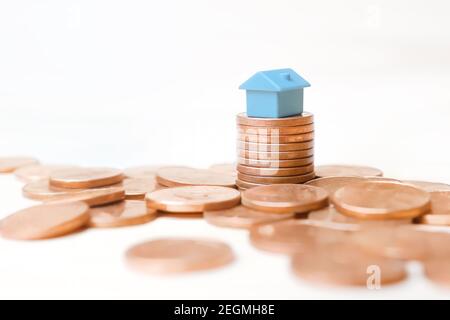 Blue toy house money coins stack on white background. Mini house model on stack coins pile money home loan concept for business property investment in Stock Photo