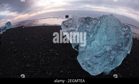 Big iceberg sparkles over black sand at Diamond beach Iceland Stock Photo