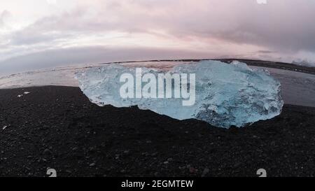 Big iceberg sparkles over black sand at Diamond beach Iceland Stock Photo