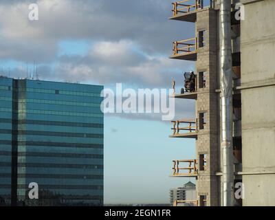 Worker on balcony at construction site mixes concrete on the background is a building and blue sky Stock Photo