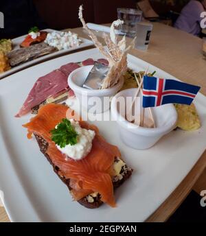 Icelandic food sample platter with fermented shark, dried fish, butter , smoked trout and lamb, with iceland flag on top Stock Photo