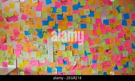 USA, Tennessee - May 28, 2017 - Multiple colored papers sticked to the wall, each one has a different note or drawing Stock Photo
