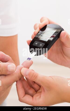 Male Patient At Doctor Checking Glucose Using Glucometer Monitor Stock Photo