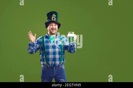 Happy guy celebrating Saint Patrick's Day and drinking beer isolated on green background Stock Photo