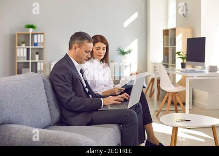 Focused business people using laptop, working on project, entering data, doing paperwork Stock Photo