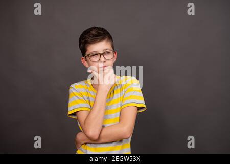 boy with glasses. thoughtful look. on a dark gray background. Stock Photo