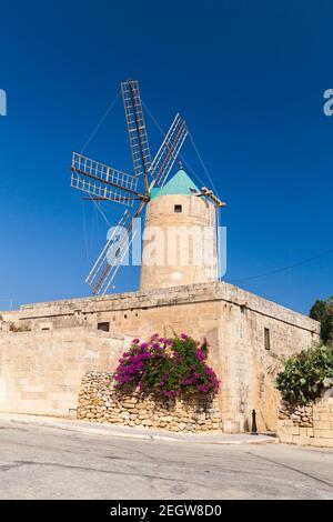 Xaghra Ggantija street view with old windmill under blue sky at sunny day. Gozo island, Malta Stock Photo