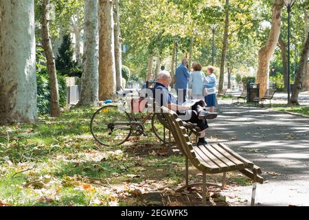 People meeting and relaxing on a sunday morning in the park on a warm autumnal day, city of Piacenza, Italy Stock Photo