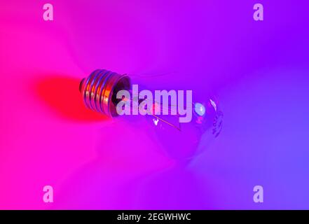 Photo of light bulb lamp in neon light. Ideea concept isolated on pink blue background, for electrician maintenance, craftsman, handyman Stock Photo