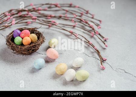 Colourful Easter eggs in bird's nest with decorative willow branches on ...