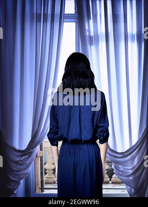 woman looking through window Stock Photo
