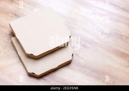 Take away pizza brown paper boxes on wooden background. Empty pizza cardboards. Front view food delivery packaging. Stock Photo