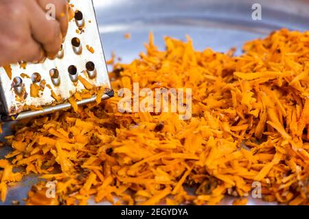 Using grater or shredder to cut turmeric roots into fine pieces for medicinal and food purposes. Stock Photo