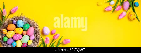 Easter - Decorated Eggs In Nest With Pink Tulips In Yellow Background Stock Photo