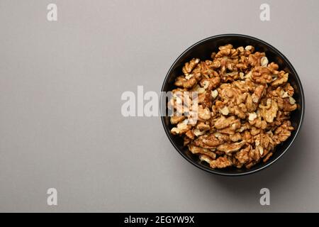 Bowl with tasty walnuts on gray background Stock Photo