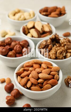 Bowls with different nuts on white textured background, space for text Stock Photo
