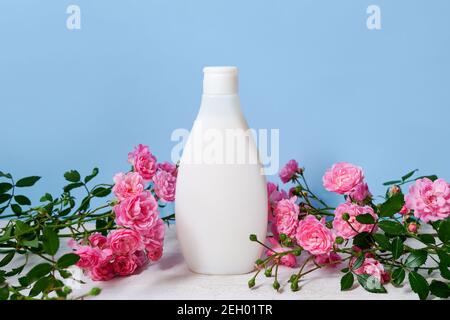 organic body lotion and fresh pink flowers on blue background, template