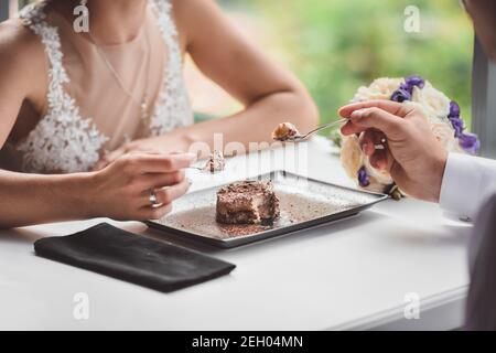 A couple in love in a cafe eating a cake. A love date in a restaurant. Hands close-up taking ice cream or dessert. 
