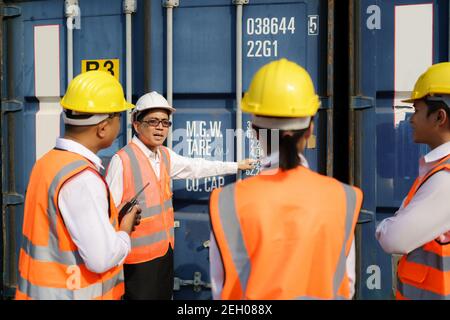 Asian foreman is explaining and teaching new training workers for various components of container to new inspection container worker. Stock Photo