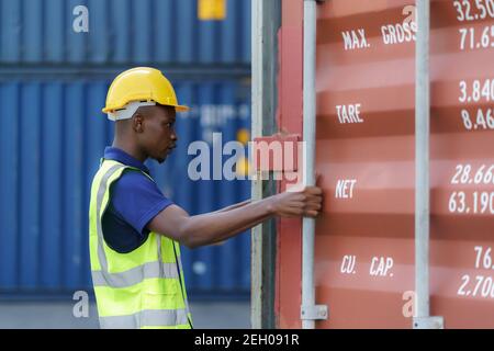 African-American black workers are opening containers for inspection and check that repairs have been completed in containers depot terminal. Stock Photo