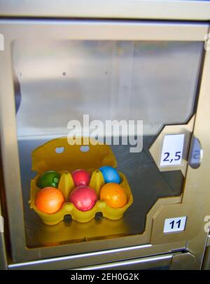 Coloured easter eggs behind glass in a self service machine Stock Photo