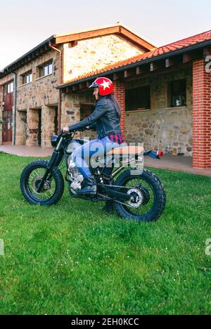 Young woman with helmet riding a custom motorbike outdoors