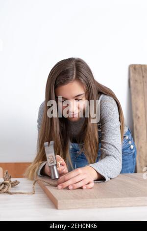 Vertical shot of a Caucasian woman working in a craft workshop with various tools and materials Stock Photo