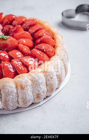 Diplomat cake or Charlotte Cake with strwaberries and lady fingers in baking  pan on a wooden table with pink background Stock Photo - Alamy