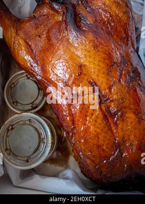 A Cantonese whole roast duck with container of sauce as package for takeaway. Stock Photo