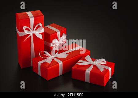 Composition of four gifts of different shapes wrapped in red wrapping paper with a white ribbon and a bow on a black background. Side view. Copy space Stock Photo