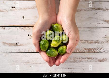 Hands with  brussel sprouts on wooden table Stock Photo