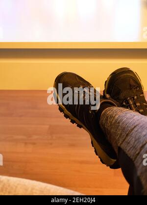 Lying on the sofa at home in slippers. Take your feet off the sofa, concept. Cleaning. Do not step on the parquet floor. Do not put slippers on furnit Stock Photo