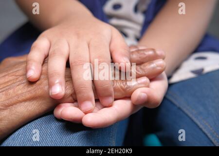 detail shot of a child holding hand of a senior women  Stock Photo