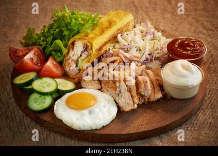 Shawarma with meat, fresh vegetables and scrambled eggs on a wooden cutting board. Stock Photo