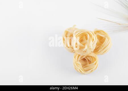 Uncooked three tagliatelle nests on white background Stock Photo