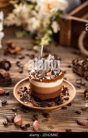 Delicious mini round chocolate and coffee cake in wooden plate on wooden table background, Stock Photo