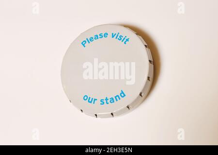 White round metal box with inscription Please visit our stand and copy space on white background Stock Photo