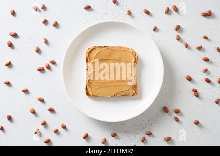 Fresh toast with peanut paste and nuts around on white background. View from above. Stock Photo
