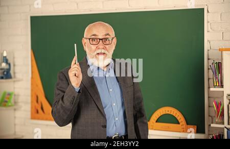 spend hours studying, back to school. protractor ruler. learn geometry easily. become good at math. stem in classroom. senior man teacher use tool at blackboard. bearded tutor in glasses. Stock Photo
